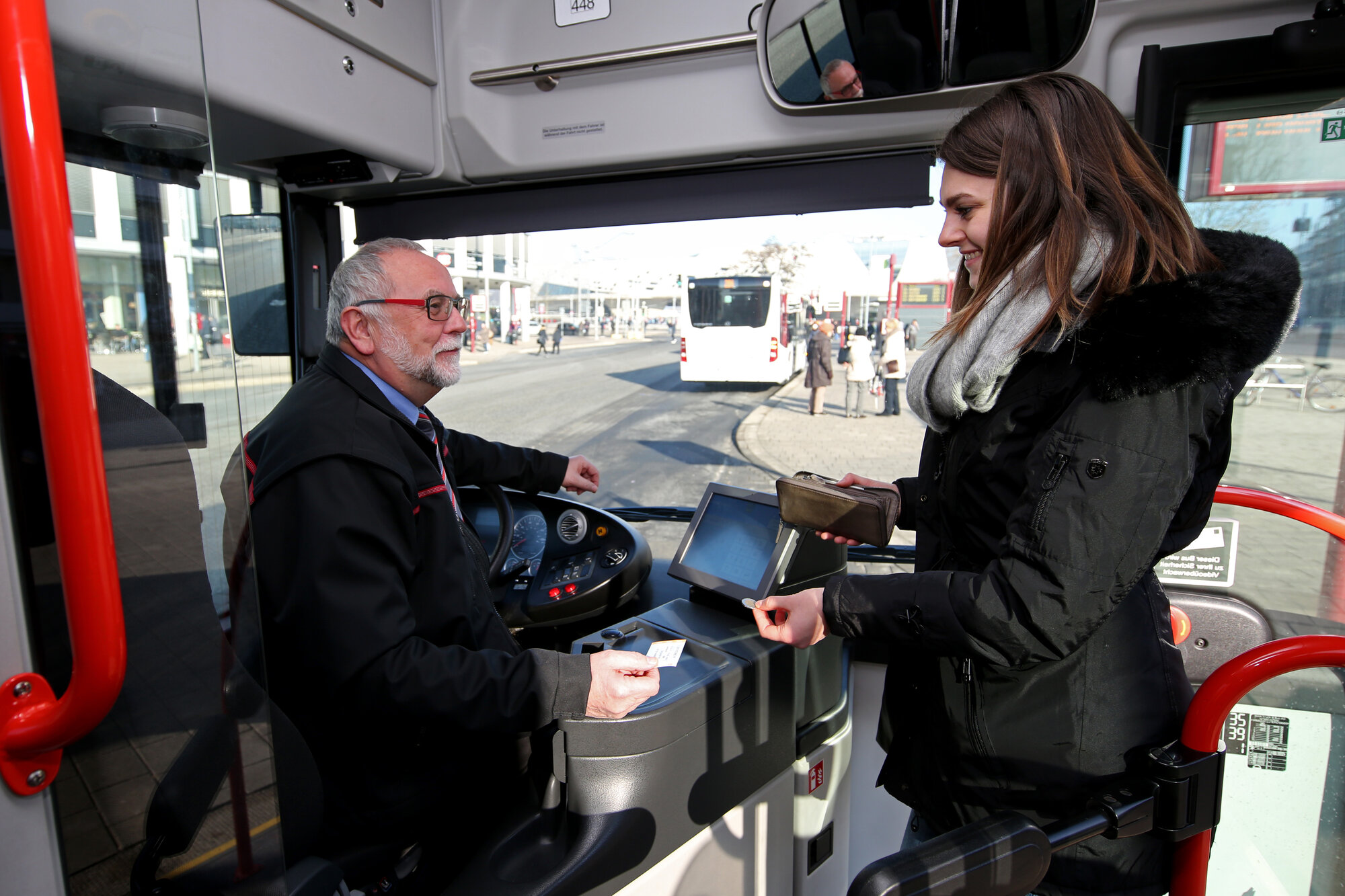 Frau kauft Fahrkarte beim Busfahrer 